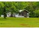 Landscaped front yard with a charming home nestled among mature trees at 505 Cedar Creek Nw Rd, Cartersville, GA 30121