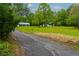 A charming property with a gravel driveway, lush green lawn, mature trees, and a detached garage on a sunny day at 505 Cedar Creek Nw Rd, Cartersville, GA 30121