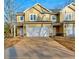 New construction townhome featuring a two-car garage and craftsman-style facade with light yellow siding and stone accents at 6860 Robinson St, Lithonia, GA 30058