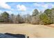 View of the backyard with lush grass and surrounding trees from the home's spacious outdoor deck at 135 Antoinette Ave, Mcdonough, GA 30252