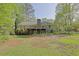 Backyard view of the two-story home featuring a large deck, brick chimney, and mature trees at 115 Beechwood Trl, Roswell, GA 30075