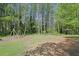 Expansive backyard featuring a classic wooden swing set surrounded by mature trees, perfect for Gathering activities at 115 Beechwood Trl, Roswell, GA 30075