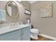 Bathroom features a blue vanity cabinet, white sink, golden faucet, oval mirror, artwork and modern toilet at 115 Beechwood Trl, Roswell, GA 30075