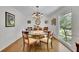 Classic dining room with a glass table, decorative chandelier, wood floors, and large window with backyard views at 115 Beechwood Trl, Roswell, GA 30075