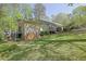 Exterior elevation of the home featuring a wooden deck, brick chimney, and sprawling green yard at 115 Beechwood Trl, Roswell, GA 30075