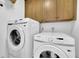 Modern laundry room with front load washer and top load dryer, overhead cabinets and white walls at 115 Beechwood Trl, Roswell, GA 30075