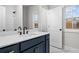 Stylish bathroom featuring a navy blue vanity with gold hardware, marble countertops, and a tiled shower at 683 Summitt Hill Way, Cumming, GA 30040