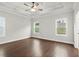 A bright main bedroom with wood floors, a ceiling fan, and two large windows at 683 Summitt Hill Way, Cumming, GA 30040