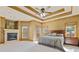 Main bedroom with tray ceiling, fireplace, carpet, and windows with natural light at 755 Peninsula Overlook, Hampton, GA 30228