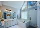 Bright bathroom with large vanity, soaking tub and glass-enclosed shower, illuminated by natural light from the A-frame window at 1052 Secret Ne Trl, Sugar Hill, GA 30518