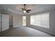 Bright, carpeted bedroom featuring large windows, a ceiling fan and doors to an ensuite bathroom and closet at 1052 Secret Ne Trl, Sugar Hill, GA 30518