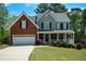 Charming two-story home with a brick and gray facade, a welcoming front porch, and a well-manicured lawn at 1052 Secret Ne Trl, Sugar Hill, GA 30518