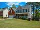 Lovely two-story home with a covered front porch, brick accents, and a lush green lawn in a neighborhood setting at 1052 Secret Ne Trl, Sugar Hill, GA 30518