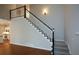 Bright foyer featuring hardwood floors and a staircase with a black and white railing, leading to the upper level of the home at 1052 Secret Ne Trl, Sugar Hill, GA 30518