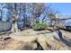 Landscaped backyard featuring a stone retaining wall, mature trees, and lush greenery for a private outdoor space at 1081 Talon Trce, Lawrenceville, GA 30043