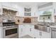 Well-lit kitchen with white cabinets, stainless steel appliances, granite countertops, and mosaic backsplash at 1248 Reilly Ln, Clarkston, GA 30021