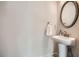 Stylish powder room with a classic pedestal sink, round mirror, and neutral wall color at 245 Fender Walk, Marietta, GA 30060