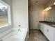Bathroom featuring a double vanity, soaking tub and large window at 80 Hawthorn Ln, Covington, GA 30014