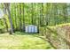 View of a backyard with lush lawn, mature trees, and a storage shed at 3719 Paul St, Douglasville, GA 30135
