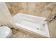 Bathroom featuring a jetted tub with shower and light tan tile surround at 4503 Rivercliff Sw Dr, Lilburn, GA 30047