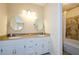 Bathroom featuring double vanity with granite counters, white cabinets, and a tub with shower at 4503 Rivercliff Sw Dr, Lilburn, GA 30047