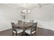 Dining room featuring hardwood floors, wainscoting, a stylish chandelier, and an adjacent living area at 811 Holly Mist Ct, Loganville, GA 30052