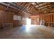 View of a large garage with wooden beam ceiling, concrete floor, and visible storage, perfect for workshop or parking at 56 Windom Dr, Carrollton, GA 30116