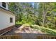 Backyard featuring a green yard, natural landscaping, and a glimpse of the home's exterior at 6048 Kings Mountain Way, Tucker, GA 30087