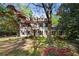 Attractive two-story house with white siding, red shutters, and mature trees with a colorful flowering groundcover at 6048 Kings Mountain Way, Tucker, GA 30087
