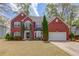 Charming two-story red brick home featuring a well-manicured lawn, shutters, and attached two car garage at 725 Martin Field Dr, Lawrenceville, GA 30045