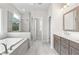 Bright bathroom with a soaking tub with glass shower, double vanity, and neutral tile floors at 685 Summitt Hill Way, Cumming, GA 30040