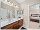 Bathroom featuring double sinks, a large mirror with vanity lighting, and access to the bedroom, combining style and functionality at 2358 New Salem Trce, Marietta, GA 30064
