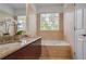 Bright bathroom with double sinks, granite counters, tub, and natural light from a window at 200 Renaissance Ne Pkwy # 219, Atlanta, GA 30308