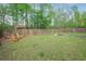 Large, grassy backyard with a wooded fence line, and a wooden chair at 527 Mossycup Dr, Fairburn, GA 30213