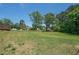 Grassy backyard with mature trees and distant views of neighboring homes at 1048 Tumblewood Trl, Lawrenceville, GA 30044