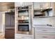 Modern stainless steel built-in double oven and cooktop, complemented by white cabinetry and subway tile backsplash at 480 Friar Tuck Cir, Covington, GA 30014