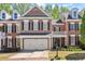 A beautiful two-story brick home featuring a two-car garage, black shutters, and manicured landscaping at 12150 Dancliff Trce, Alpharetta, GA 30009