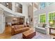 Open-concept living area with tall windows, hardwood floors, comfortable seating, and staircase access to the second floor at 12150 Dancliff Trce, Alpharetta, GA 30009