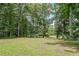 Expansive backyard with mature trees, lush grass, and distant view of a tranquil lake at 527 Gaddis Rd, Canton, GA 30115