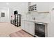A modern bar area features white cabinets, a wine rack, a sink, a beverage fridge, and a stylish backsplash at 626 Oakbourne Way, Woodstock, GA 30188