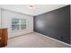 Clean, empty bedroom with carpet, a large window, and a dark accent wall at 626 Oakbourne Way, Woodstock, GA 30188