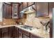 Close-up of kitchen cooktop with stainless vent hood, backsplash, and granite countertops at 626 Oakbourne Way, Woodstock, GA 30188
