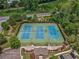 Aerial view of three well-maintained tennis courts, surrounded by lush landscaping and mature trees at 626 Oakbourne Way, Woodstock, GA 30188
