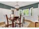 Dining area features a wood table, large bay windows, a modern chandelier, and wainscoting at 3040 Greenfield Dr, Marietta, GA 30068