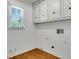 Bright laundry room featuring built-in white cabinets, updated fixtures and wood flooring at 3040 Greenfield Dr, Marietta, GA 30068