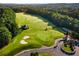 Aerial view of a lush community golf course with a clubhouse, golf carts and wooded surroundings at 629 Gold Valley Pass, Canton, GA 30114