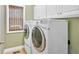 A dedicated laundry room with a front-load washer and dryer and white cabinets at 7801 Windswept Way, Douglasville, GA 30135