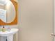 Bright half bathroom featuring a pedestal sink, wooden-framed mirror, and neutral wall color at 7801 Windswept Way, Douglasville, GA 30135