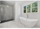 Modern bathroom with marble walk-in shower, freestanding tub under a window, and marble tile flooring at 3920 Bellair Dr, Marietta, GA 30066