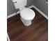 Bathroom featuring a white toilet against a dark wood floor and grey wall at 9399 Whaleys Lake Ln, Jonesboro, GA 30238